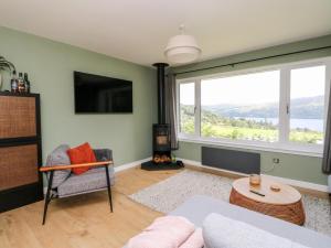 a living room with a couch and a large window at Beech Cottage in Aberfeldy