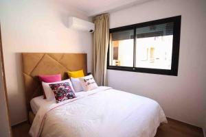 een slaapkamer met een wit bed met kussens en een raam bij Glamorous Marrakech in Marrakesh
