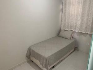 ein kleines Bett in einem Zimmer mit Fenster in der Unterkunft Quitinete Aconchegante Prq Pelinca in Campos dos Goytacazes