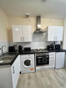 una cocina con armarios blancos, lavadora y fregadero en 2 Bedroom Apartment with Balcony, en Oxford