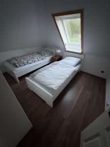 two beds in a small room with a window at Ferienwohnung am See in Heilshoop