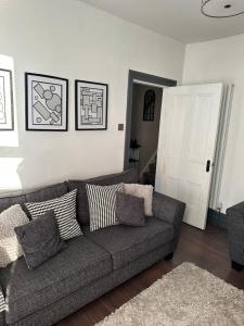 a living room with a gray couch with pillows at 3 Bedroom House on Beatles Famous Road in Liverpool