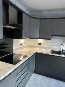 a kitchen with black and white cabinets and a sink at 3 Bedroom House on Beatles Famous Road in Liverpool