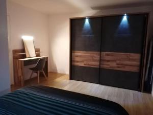 a bedroom with a bed and a desk next to a closet at Appartement Paris Roissy Astérix in Louvres