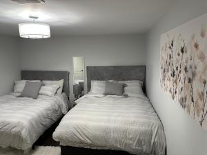 a bedroom with two beds and a painting on the wall at Luxurious and modern one bedroom basement suite. in Brampton