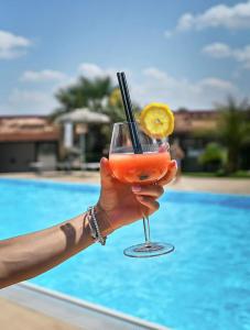 una persona sosteniendo una bebida frente a una piscina en Egò Salento, en Galatina