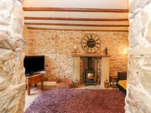 a room with a stone wall with a clock and a fireplace at The LA'AL Cragg in Kirkby Stephen
