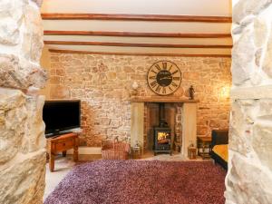 Zimmer mit einer Steinmauer, einer Uhr und einem Kamin in der Unterkunft The LA'AL Cragg in Kirkby Stephen