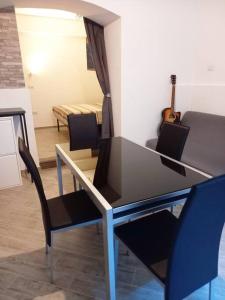 einen Tisch und Stühle im Wohnzimmer mit Gitarre in der Unterkunft 'Al Vico Dante' in Loceri