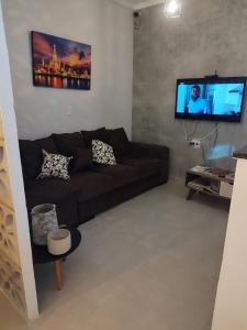 ein Wohnzimmer mit einem braunen Sofa und einem Flachbild-TV in der Unterkunft HOTEL E RESTAURANTE LIMA in Luis Eduardo Magalhaes