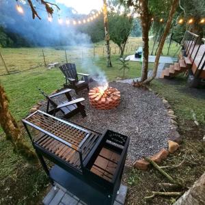 a grill in a yard with two chairs and a fire pit at Reserva Guimarães in Cambara do Sul