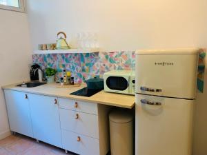 uma cozinha com um frigorífico branco e um micro-ondas em cosy studio design with modern bathroom em Vauréal