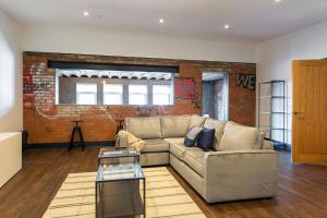 a living room with a couch and a brick wall at The Kingsway- 2 Bedroom Central Swansea Apartments By StayRight in Swansea