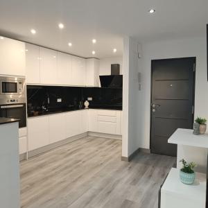 Una cocina con gabinetes blancos y electrodomésticos negros. en Apartamento Cristina 3 - Playa Arenal Bol, en Calpe