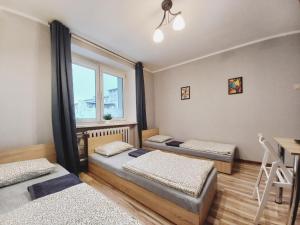 ブィドゴシュチュにあるTanie spanie na Grunwaldzkiej - ZAMELDOWANIE BEZOBSŁUGOWE-のベッド3台と窓が備わる客室です。