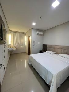 a bedroom with a large white bed and a television at Hotel PetroShop in Palmas