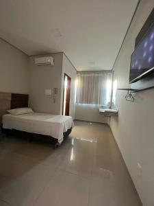 a bedroom with a bed and a flat screen tv at Hotel PetroShop in Palmas