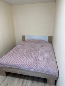 a small bedroom with a bed with a pink comforter at Apartment in Liepāja