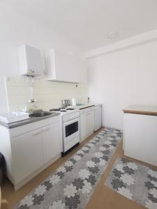 a kitchen with white appliances and a rug at Apartman Monaco in Kraljevo