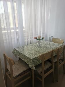 a table with a vase of flowers and two chairs at Apartman Monaco in Kraljevo