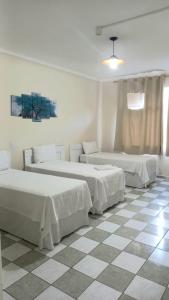 a bedroom with two beds and a checkered floor at Suite Independente Arouche Duplo ou Triplo in Sao Paulo