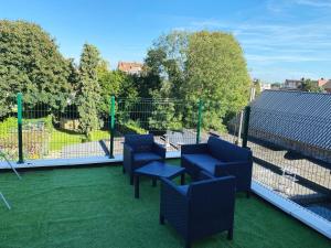 un patio con sillas azules y una mesa en el césped en Sweet home en Bruselas