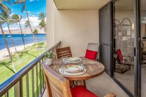 uma varanda com uma mesa e cadeiras e o oceano em Sugar Beach Resort 328 condo em Kihei