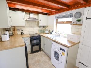 a kitchen with white cabinets and a washer and dryer at The Cottage 16 Northside in Patrington