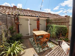 a small patio with a wooden table and chairs at The Cottage 16 Northside in Patrington