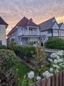 a large white house with a fence and flowers at Océan Waves in Gorleston-on-Sea