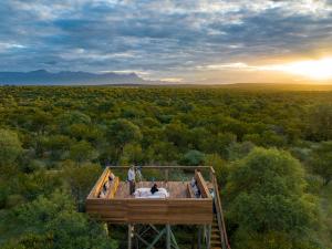 Dos personas de pie en una plataforma de observación en el bosque. en Oase by 7 Star Lodges - Greater Kruger Private 530ha Reserve, en Hoedspruit
