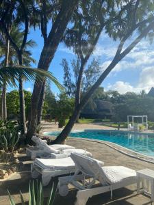 een rij witte ligstoelen naast een zwembad bij Kilili Baharini Resort & Spa in Malindi