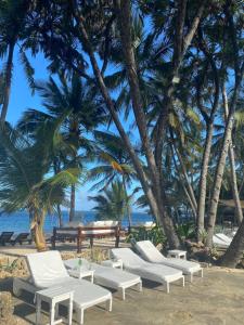 a beach with white lounge chairs and palm trees at Kilili Baharini Resort & Spa in Malindi