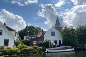 a boat parked in front of a house on a river at The Great Hideaway in Vreeland +17 photos