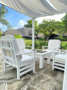 dos sillas blancas y una mesa bajo una sombrilla blanca en Kilili Baharini Resort & Spa, en Malindi