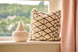 a window with a pillow and a vase on a window sill at Wood End View - Traditional Top-and-Bottom House in Hebden Bridge