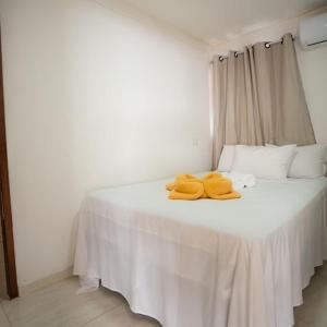 uma cama branca com duas toalhas amarelas em Pousada Villa Costeira em Maragogi