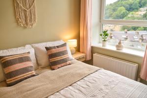 una camera da letto con letto, cuscini e finestra di Wood End View - Traditional Top-and-Bottom House a Hebden Bridge