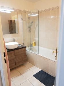La salle de bains est pourvue d'une baignoire, d'un lavabo et d'une douche. dans l'établissement Cosy Home Paris, à Carrières-sous-Poissy