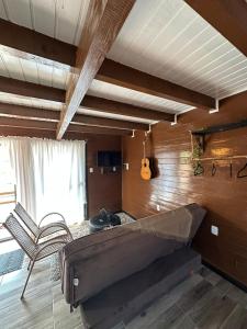 Cette chambre comprend un lit, une chaise et une guitare. dans l'établissement Chalés Cânions do Brasil, à Praia Grande