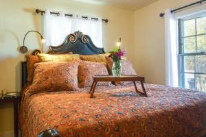 a bed with a table with a vase of flowers on it at Cozy Adobe Casita 1 Mile to Santa Fe Plaza! in Santa Fe
