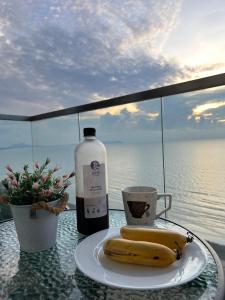 two bananas on a plate on a table with a bottle of wine at MrK Penthouse at Timurbay in Kuantan