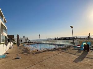 una piscina junto a una playa con sillas en Appart de Luxe front de mer Prestigia Plage des Nations en Salé