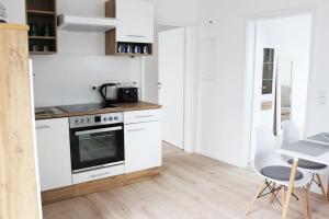 a kitchen with white appliances and a table and chairs at Schöne EG-Neubauwohnung in Bad Soden in Bad Soden am Taunus