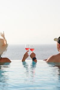 Villa Sunset Aura - Amazing Sea & Sunset View في Klouvas: شخصين يحملون كؤوس من النبيذ في حمام السباحة