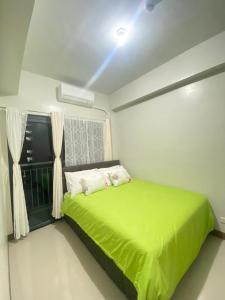 een slaapkamer met een groen bed en een raam bij 2BR Irish Luck Holiday Apartment in Manilla