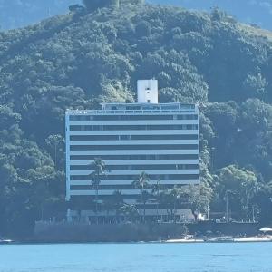 un grande edificio con palme di fronte a una montagna di Apartamento Pé na Areia a Caraguatatuba