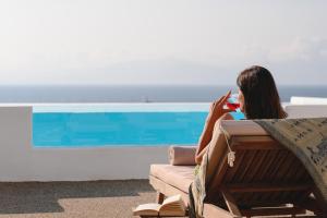 a woman sitting in a chair looking at her cell phone at Villa Sunset Aura - Amazing Sea & Sunset View in Klouvas