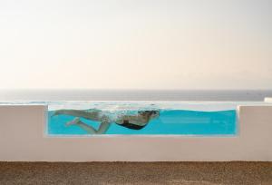 Villa Sunset Aura - Amazing Sea & Sunset View في Klouvas: وجود امرأة تسبح في مسبح بالقرب من المحيط
