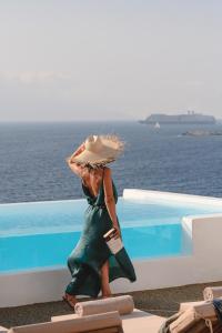 a woman in a green dress and hat sitting next to a pool at Villa Sunset Aura - Amazing Sea & Sunset View in Klouvas +86 photos